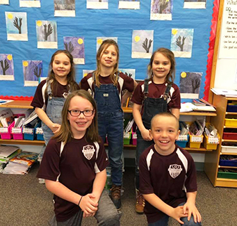 Five happy students posing for a picture in the classroom