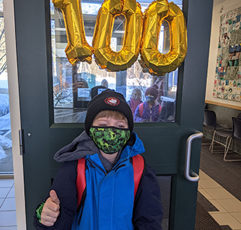 Spirited student posing for a picture in front of 100 Days of School Sign