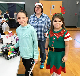 Students with adult attending a holiday event in the school gym